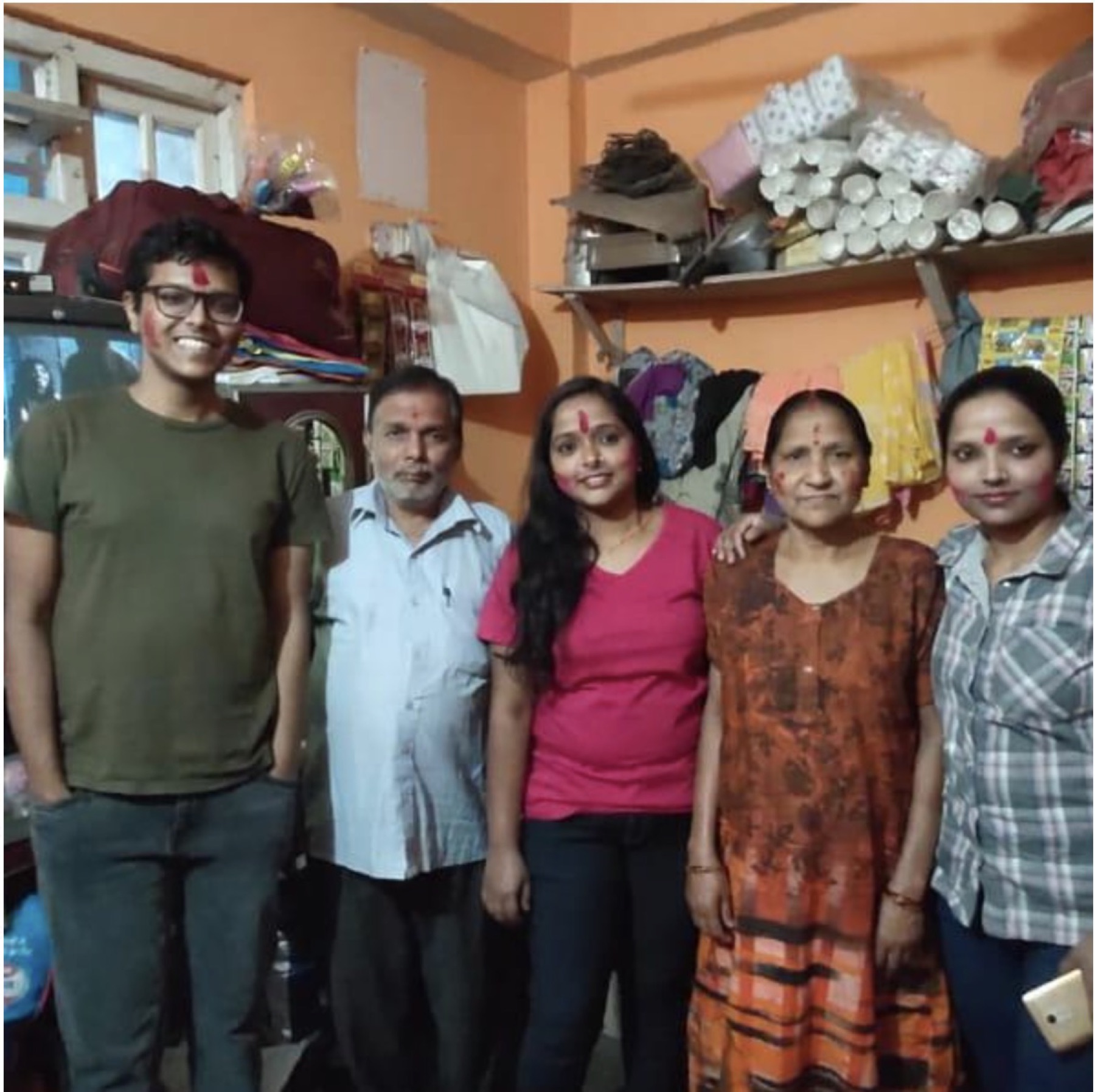 Shri Dharamnath Prasad standing indoors with his family